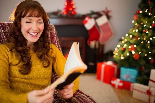 Rousse heureuse lecture sur le fauteuil à noël