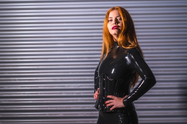 Rousse en latex, un haut noir et un pantalon moulant