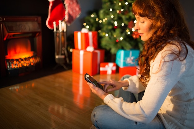 Rousse souriante à l&#39;aide de smartphone à Noël