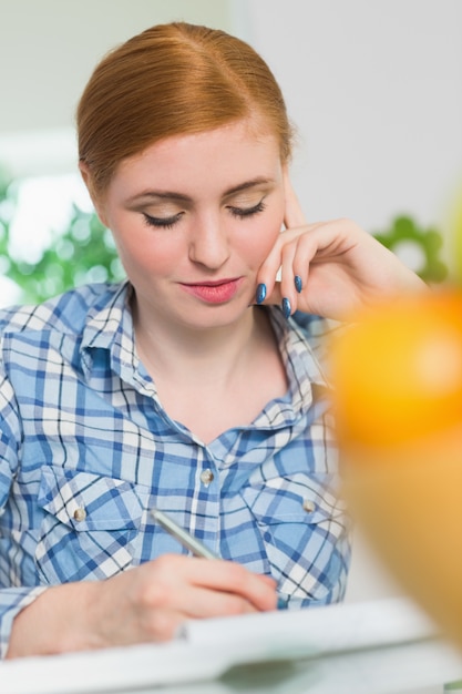 Rousse souriante écrivant à son bureau