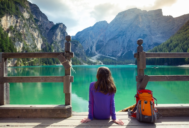 Routard fille assise sur une jetée et regardant le lac de Braies