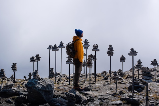 Photo un routard vêtu d'une veste jaune et d'un chapeau se détend dans les montagnes suisses avec des autels en pierre