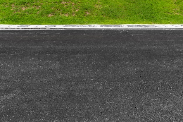 Route asphaltée avec des rayures et de la texture de l&#39;herbe verte