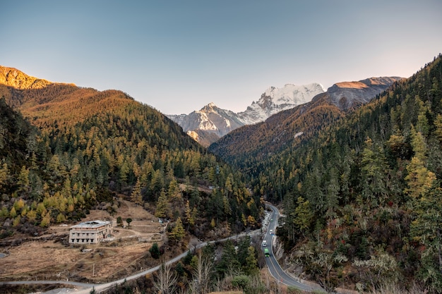 Route asphaltée avec des voitures dans la vallée d'automne avec la montagne