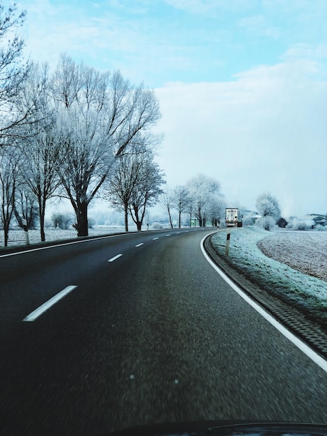 Photo une route au milieu d'arbres nus contre le ciel