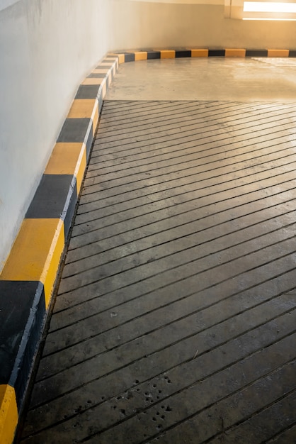 Route en béton et rampe avec bordure jaune et noire dans le bâtiment