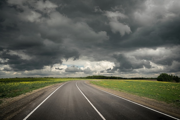 Route de campagne d'été avant l'orage. Ciel dramatique.