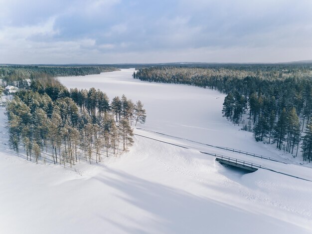 Route de campagne d'hiver sur le pont sur le lac gelé Finlande vue aérienne
