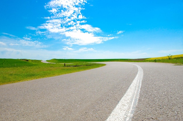 Route de campagne par champ rural contre le ciel