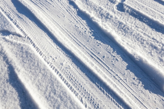 Route à la campagne, située dans le domaine. Période d'hiver de l'année, sur la route, il y a de la neige et vous pouvez voir des ornières à la surface. Photo en gros plan