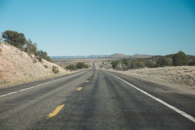 Une route de campagne vide traversant un paysage aride contre un ciel bleu clair