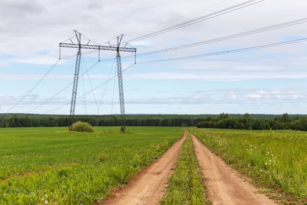 La route dans le champ près de la ligne électrique. Beau paysage