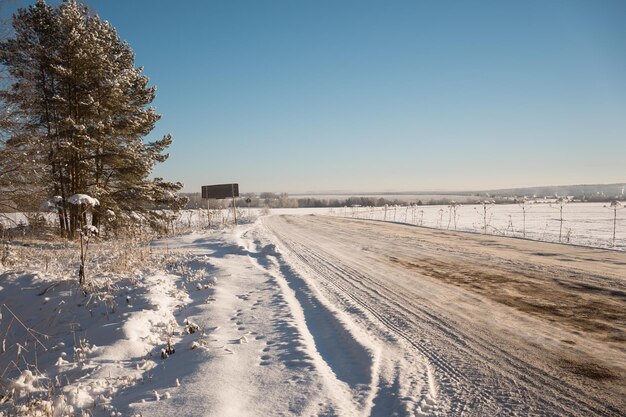 Route enneigée de campagne dans le pré en journée ensoleillée d'hiver