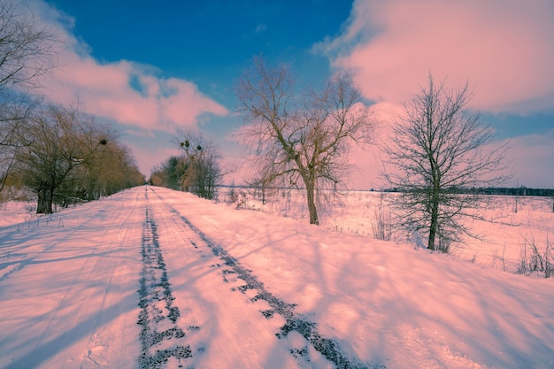 Route enneigée de pays en hiver pendant le coucher du soleil