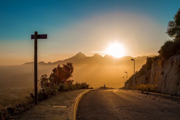 route sur le fond des crêtes des montagnes à l'horizon avec le soleil couchant