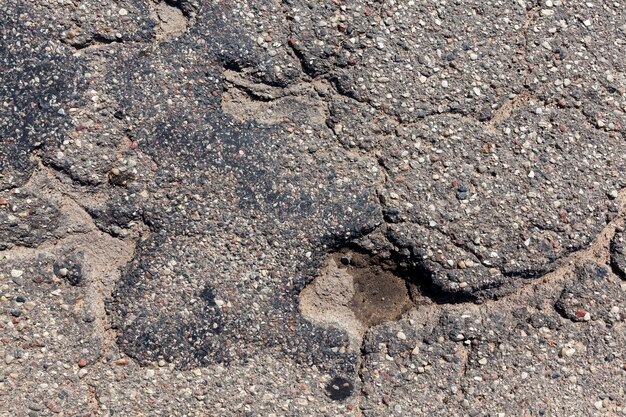 Une route goudronnée avec beaucoup de trous et de nids-de-poule