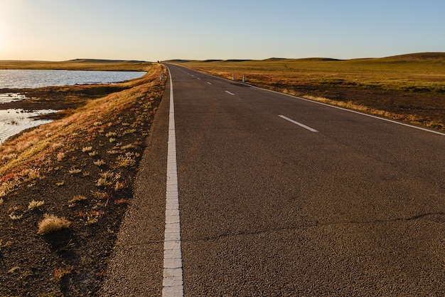 Route goudronnée dans la steppe mongole le long d&#39;un petit lac