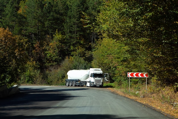 La route goudronnée descend à flanc de montagne dans la forêt le soir