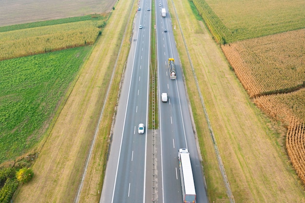 Route goudronnée droite passant par des champs jaune-vert