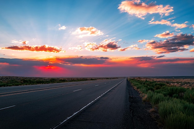 Route goudronnée vide d'autoroute et beau paysage de coucher du soleil de ciel