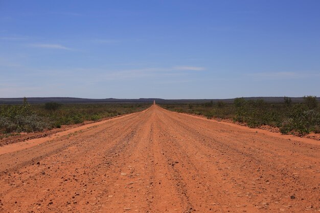 La route de gravier du sable rouge, la route de l'outback, la route vers la brousse australienne, la route éloignée de l'Outback.