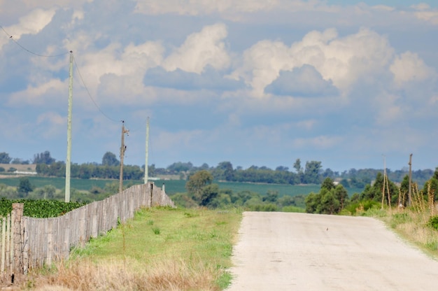 Route de gravier solitaire avec une clôture sur le côté gauche et un horizon plein de nuages orageux