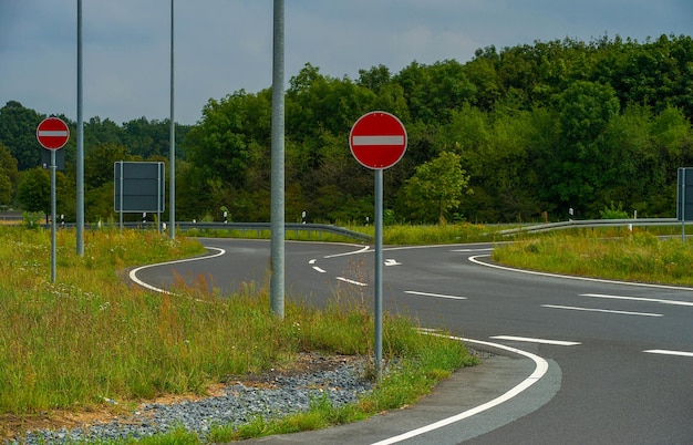 Route avec panneaux interdits sur fond de nature verdoyante.