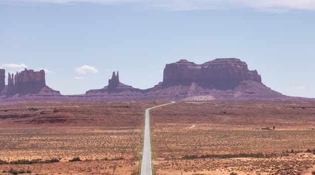 Route panoramique dans le désert aride avec des montagnes rocheuses rouges en arrière-plan