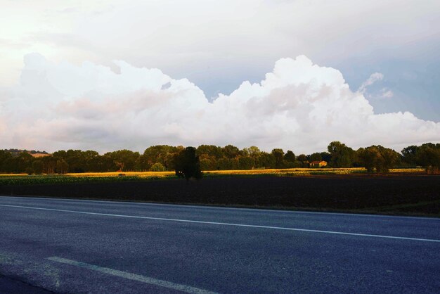 Route par champ contre un ciel nuageux