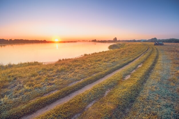 Route rurale près du lac au lever du soleil