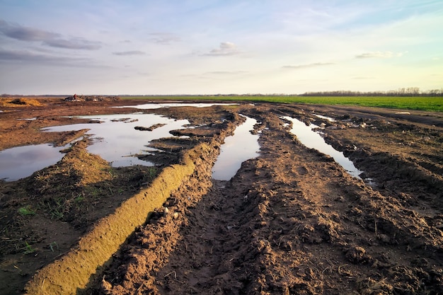 Route sale avec de la boue et des flaques d'eau sur le terrain