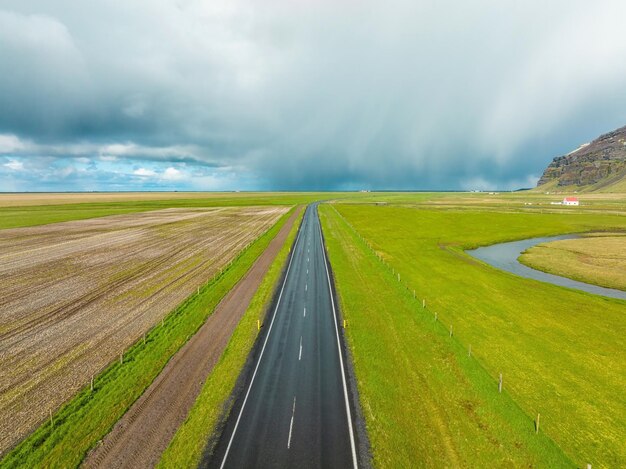 Route sans fin dans les montagnes et les collines nuageuses de l'islande par temps nuageux ensoleillé