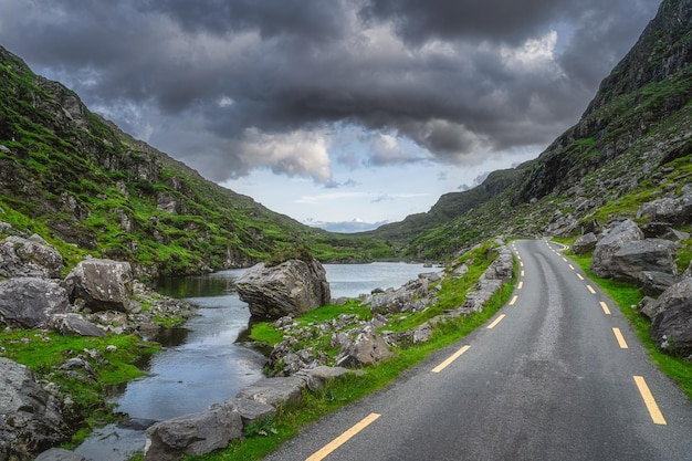 Une route sinueuse traversant le fossé de Dunloe avec le pont des vœux de pierre de la vallée noire d'Irlande