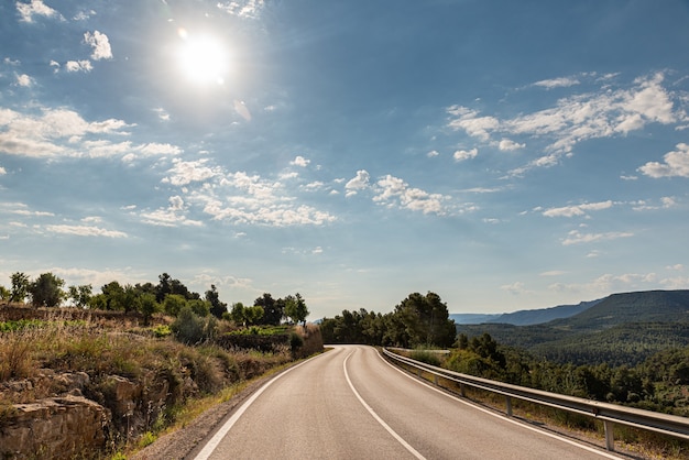 Route vers l'horizon entre montagnes et nature verdoyante et avec lever de soleil