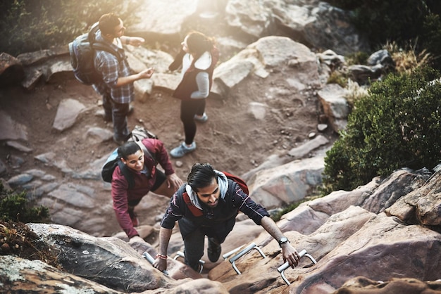 En route vers le sommet Photo d'un groupe d'amis escaladant une échelle lors d'une randonnée dans les montagnes