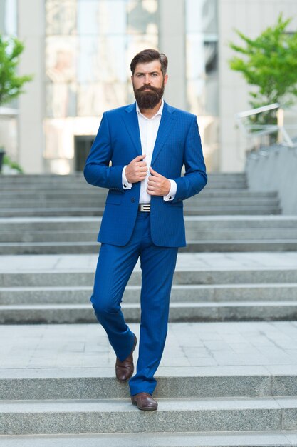 En route vers le succès Marcher dans la rue Hipster mature avec barbe dans les escaliers Homme barbu dans le centre d'affaires Homme brutal confiant marchant dans la rue Homme d'affaires en vêtements formels Gens d'affaires