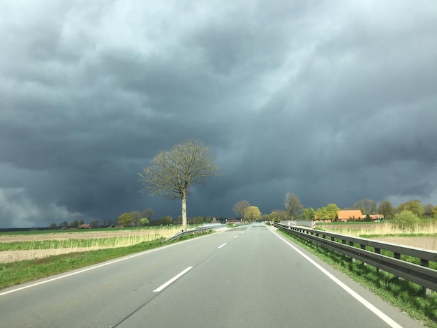 Une route vide contre un ciel nuageux