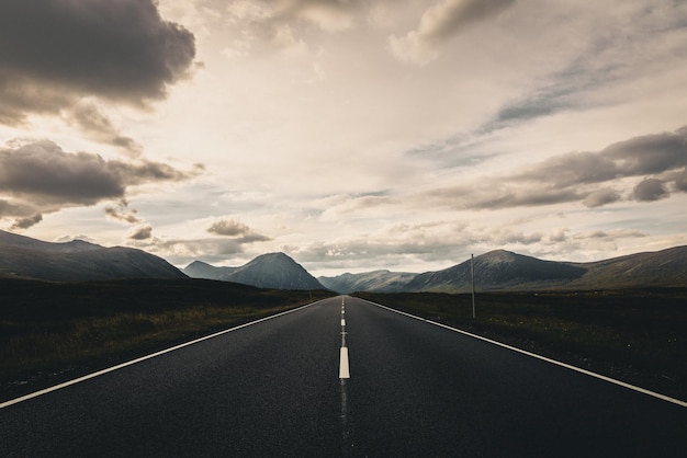 Une route vide menant vers les montagnes contre le ciel.
