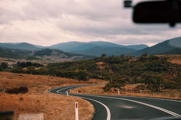 Photo une route vide menant vers les montagnes vue à travers le pare-brise d'une voiture