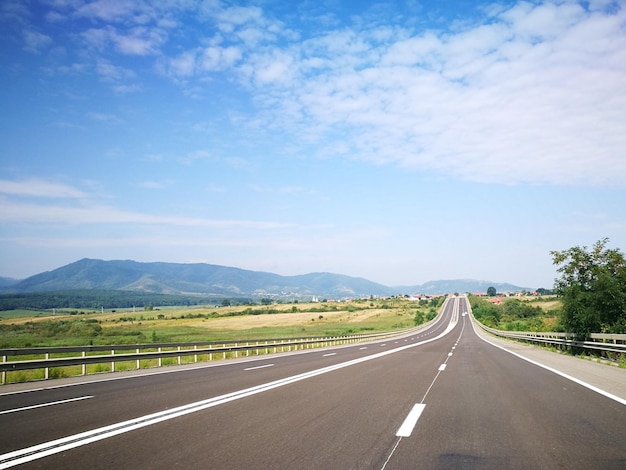 Une route vide par les montagnes contre le ciel bleu