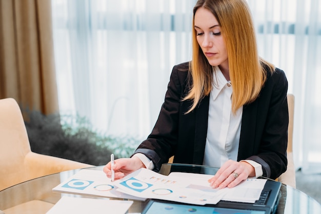 Routine de bureau. Femme travaillant avec des papiers assis à son bureau