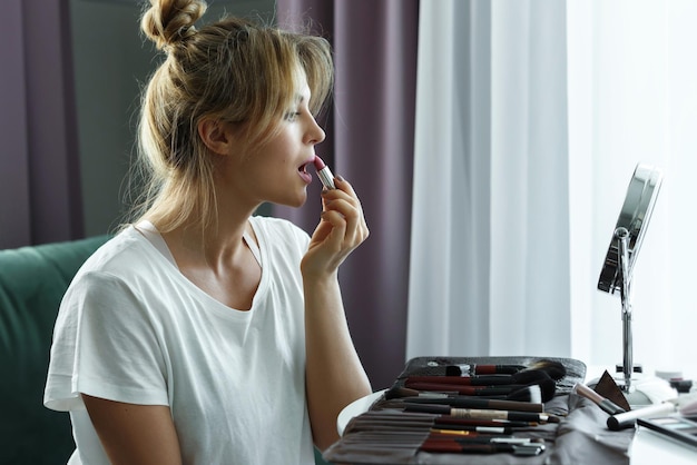 Routine de maquillage à la maison. Belle jeune femme appliquant le tube de rouge à lèvres.