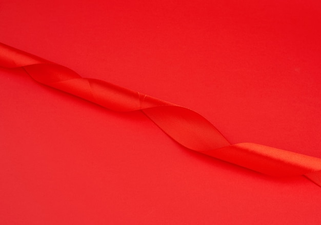 Ruban brillant en soie rouge torsadé sur fond rouge, élément de conception festive