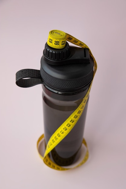 Ruban centimétrique torsadé jaune enroulé autour d'une vue de dessus de bouteille d'eau de sport