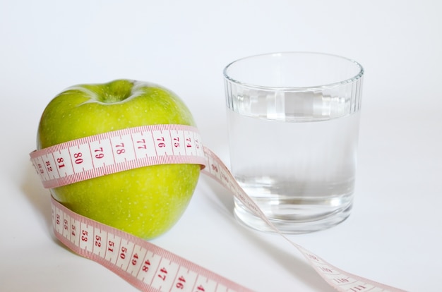 Ruban à mesurer autour d&#39;une pomme verte et d&#39;un verre d&#39;eau