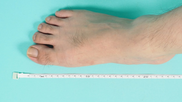 Ruban à mesurer dans les mains pieds nus et jambes sur fond vert menthe ou bleu Tiffany.