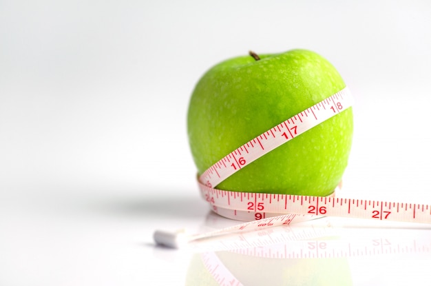 Ruban à mesurer enroulé autour d'une pomme verte comme symbole de l'alimentation