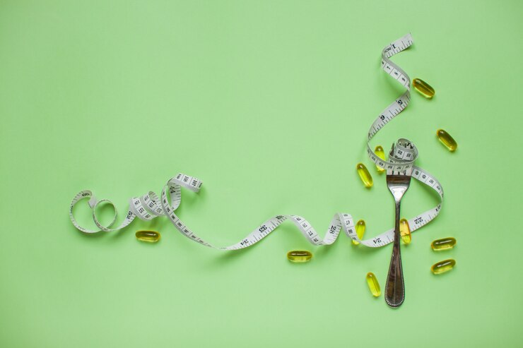 Ruban à mesurer sur une fourchette, des capsules et des pilules amaigrissantes