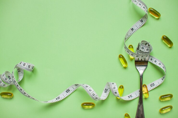 Ruban à mesurer sur une fourchette, des capsules et des pilules amaigrissantes