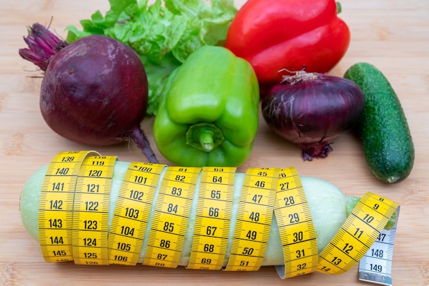 Ruban à mesurer jaune et légumes sur une planche à découper en bois. Régime de mode de vie sain.